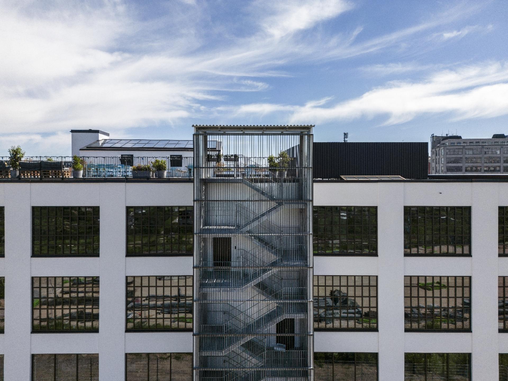 Også facaden mod gården er blevet åbnet op og tilført et industrielt look med store, småsprossede vinduespartier. På toppen til venstre ses den nyetablerede tagterrasse. Foto: Kontraframe