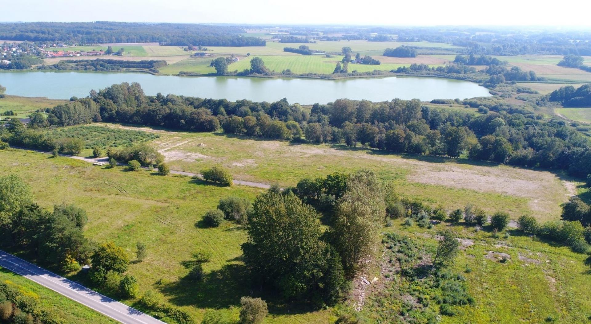 Her lå der engang en spånpladefabrik, men siden 2007 har grunden stået ubrugt hen. Nu er der åbnet op for et helt nyt boligområde med tæt nærhed til både skov og sø. Boligselskabet Sjællands almene boliger forventes at stå klar i oktober 2025. Foto: Næstved Kommune