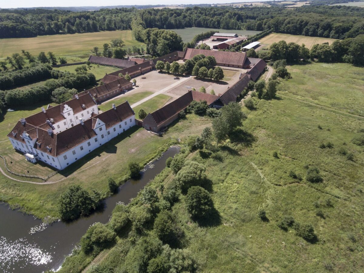 Bidstrup er et storslået barokanlæg med en trefløjet, hvidkalket, hovedbygning fra 1698 omgivet af et lukket anlæg af store rødmurede avlsbygninger. Foto: Historiske Huse.