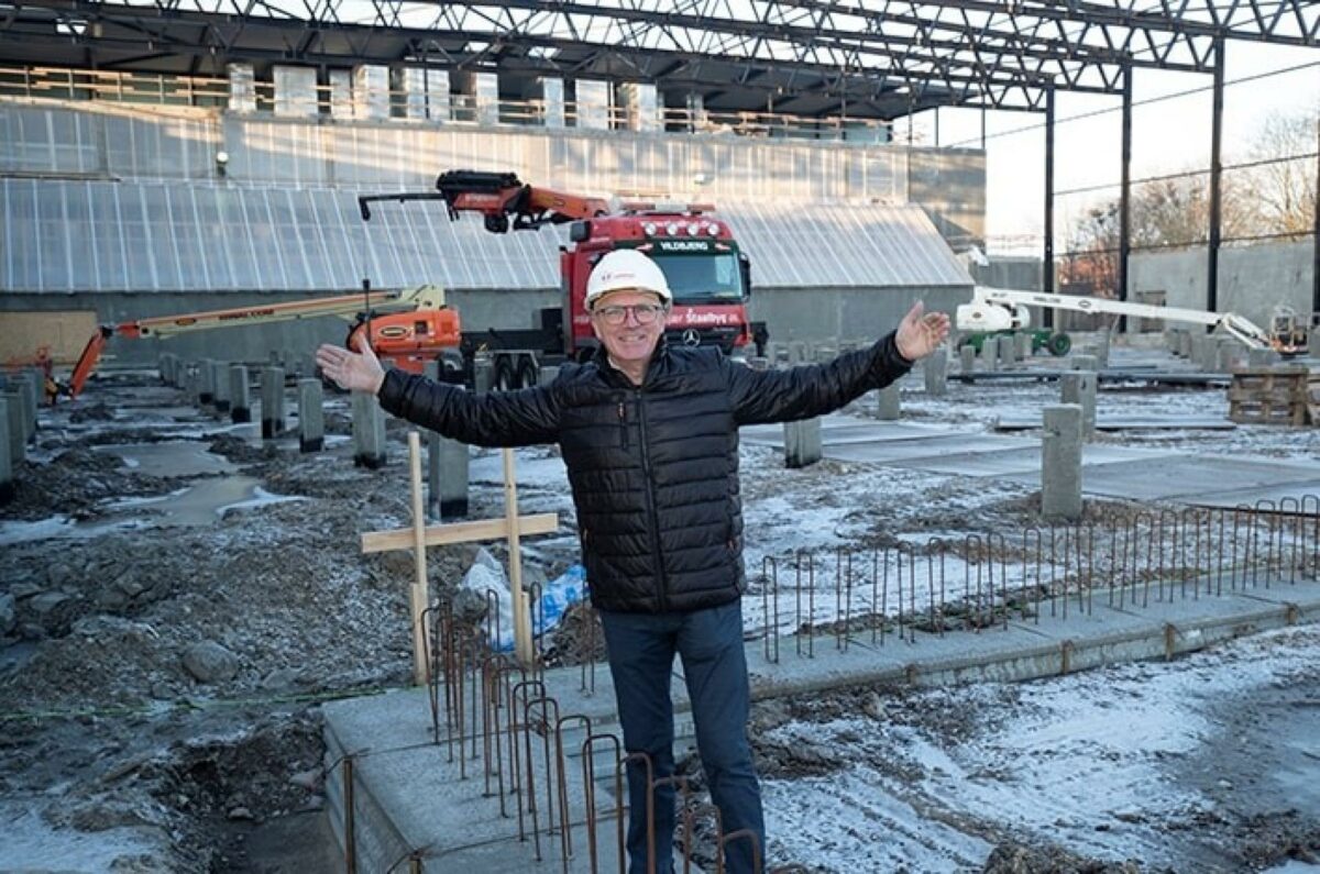 Direktør Carsten Larsen slår begejstret ud med armene. Han står på dét, der bliver gulvet i Arena Hillerød, som støt og roligt tager form. Pressefoto.