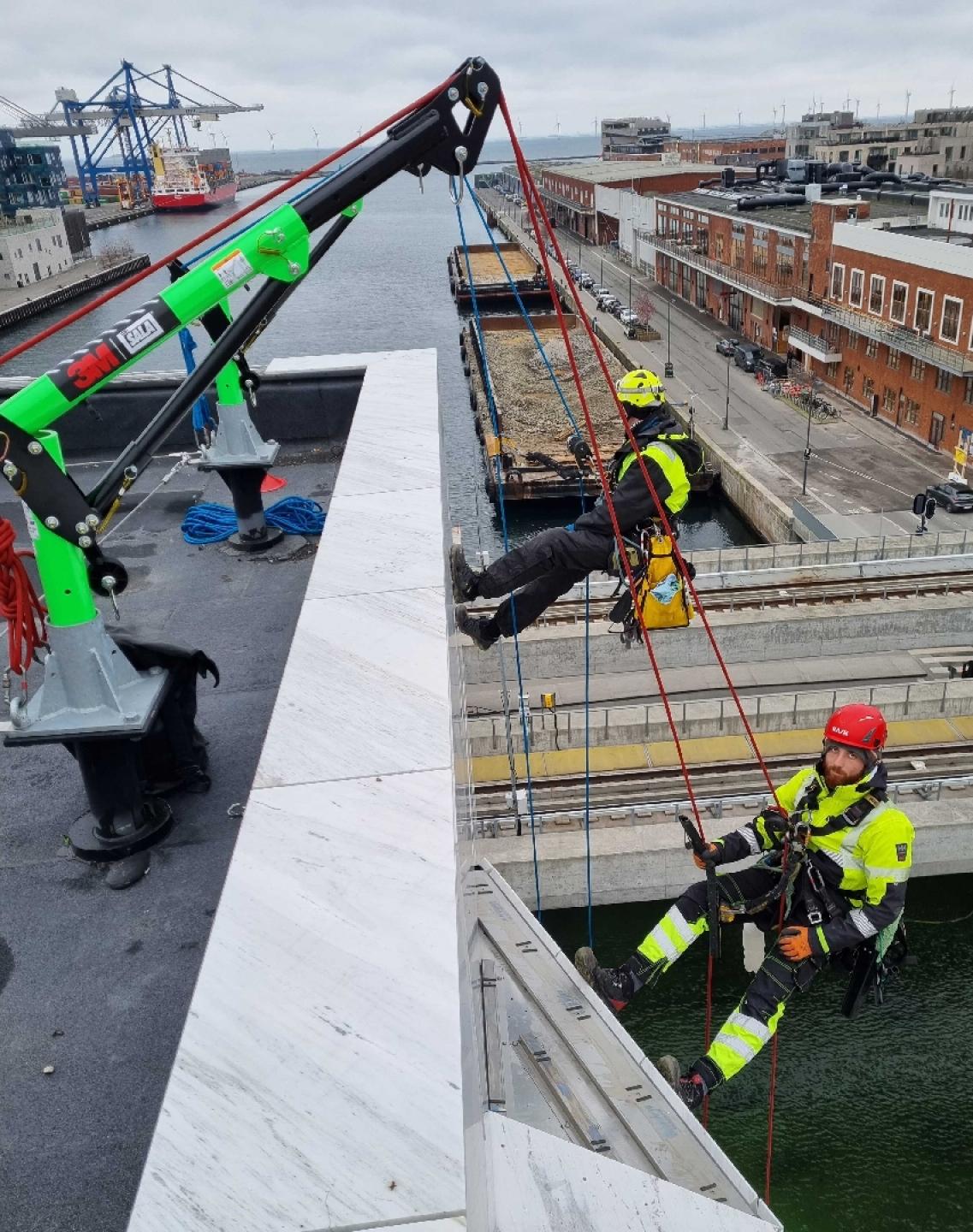 Erhverv og politiksklatrere fra Rebteknikeren på vej ud over kanten i Københavns Nordhavn. De arbejder med liner fastgjort til en Davit-arm.