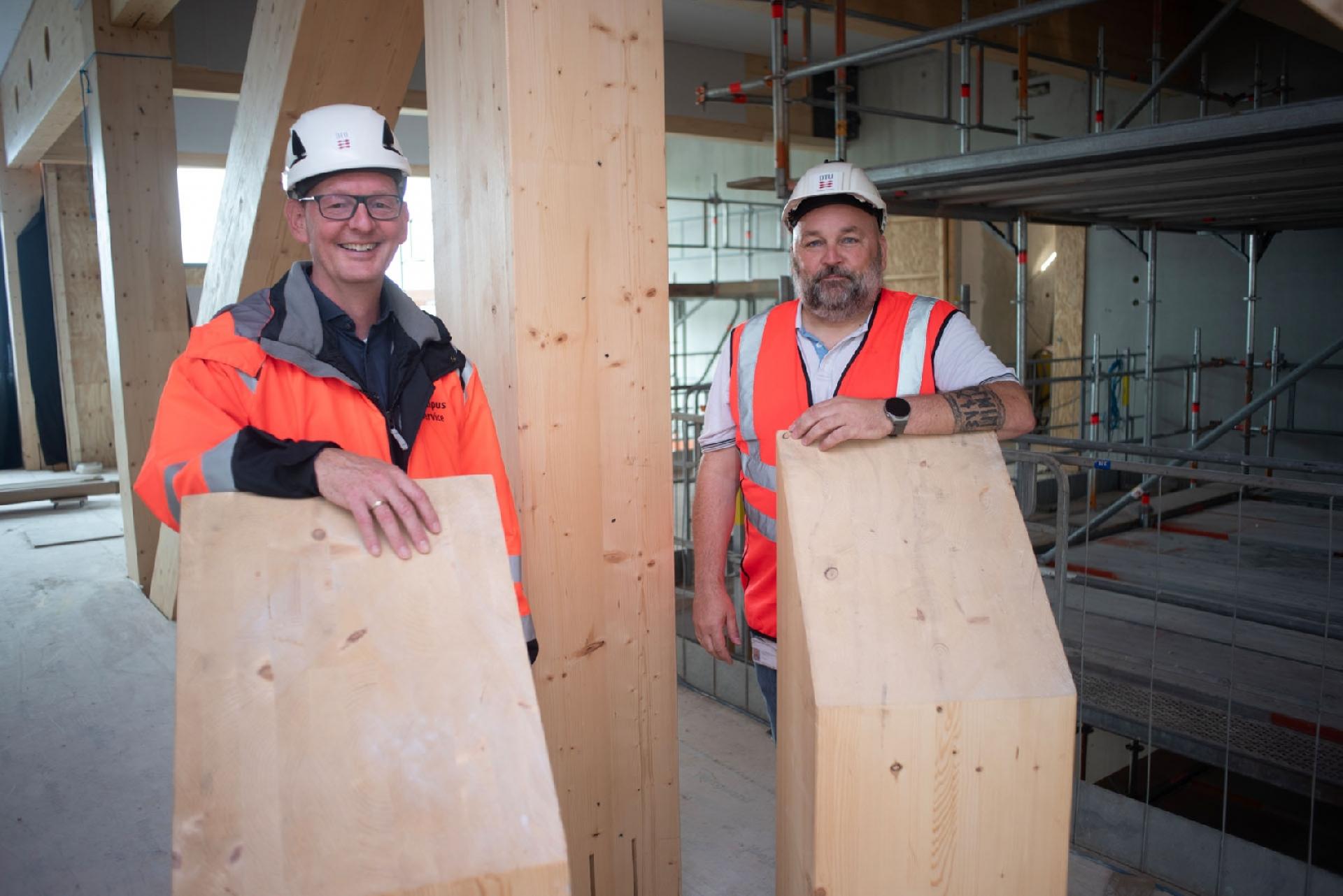 Ben Kahn, der er bygherrechef i Campus Service, og projektleder Nicolai Brogaard Bredal-Jørgensen ses her ved den imponerende trækonstruktion, der kommer til at give bygningens indre et meget markant, visuelt udtryk. Foto: Henrik Malmgreen