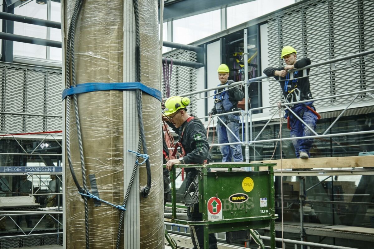 Klokken vejer tre tons og måtte hejses tredive meter op i luften for at kunne sænkes ned igennem taget i Dokk1. Foto: Byggeriets Billedbank.