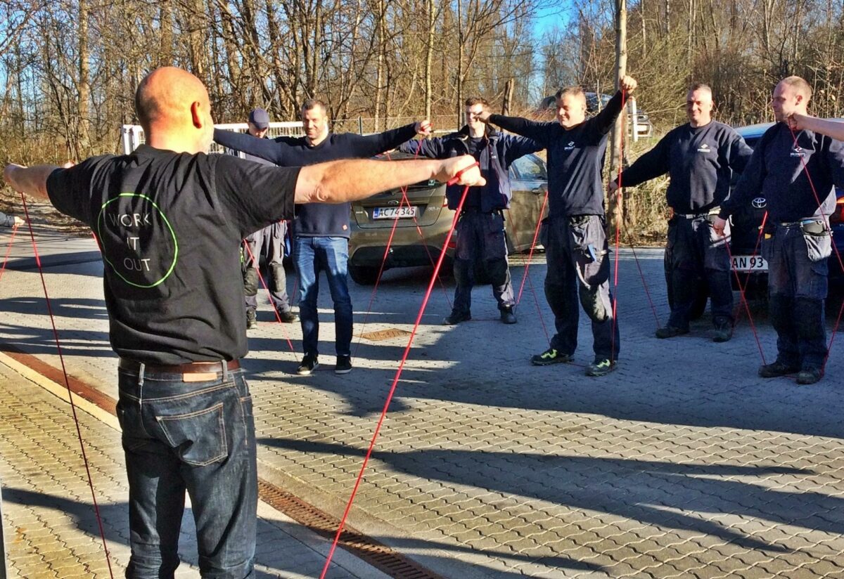 Motion indgår - som her hvor en gruppe medarbejdere udnytter formiddagens kaffepause til fælles udstrækning og styrkelse af kroppens muskler - centralt i sikkerhedskulturen hos John Jensen VVS, der over det sidste års tid helt har elimineret løfteskader.