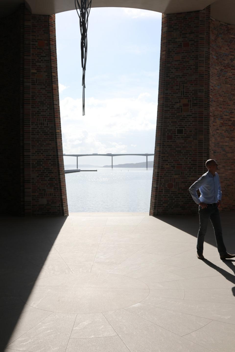 Morten Teilmann-Jørgensen viser rundt i underetagen, hvor Vejlefjordbroen kan anes i baggrunden. Foto: Thøger Raun. 