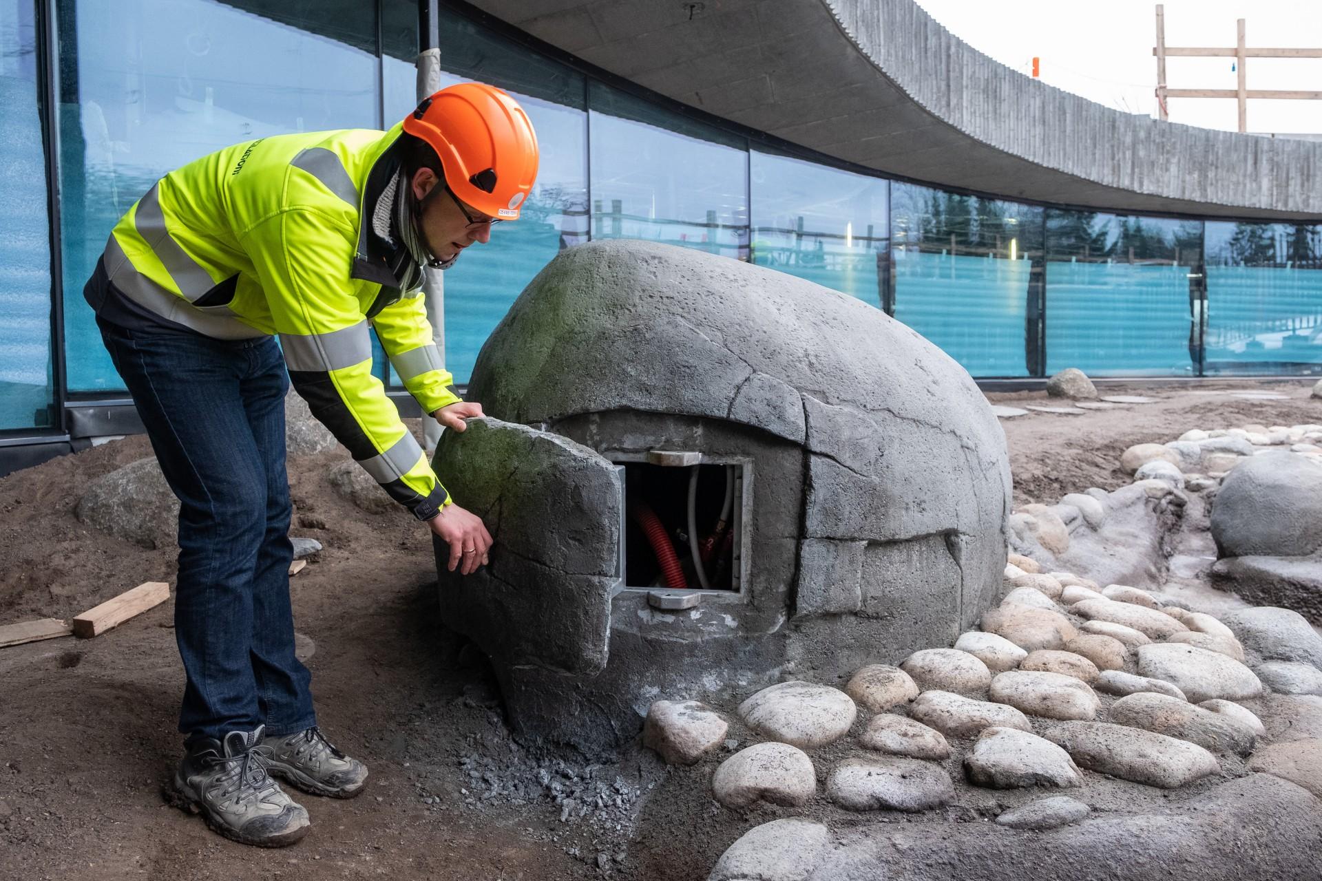Projektleder Christian Houmøller Christensen fra C5 VVS-Teknik A/S demonstrerer, hvordan installationen kan nås gennem en luge i den færdige sten.