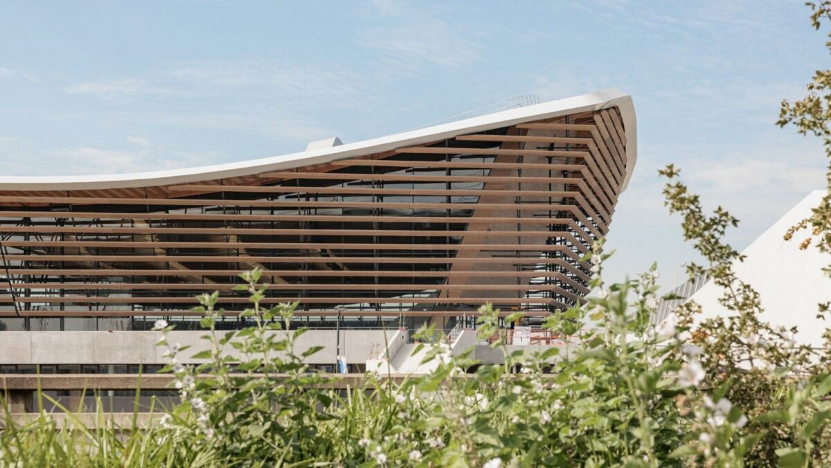 Træ, solceller og tribunestole produceret af genbrugsplast. Svømmearenaen med tribuner på tre sider, kan huse 5.000 tilskuere.