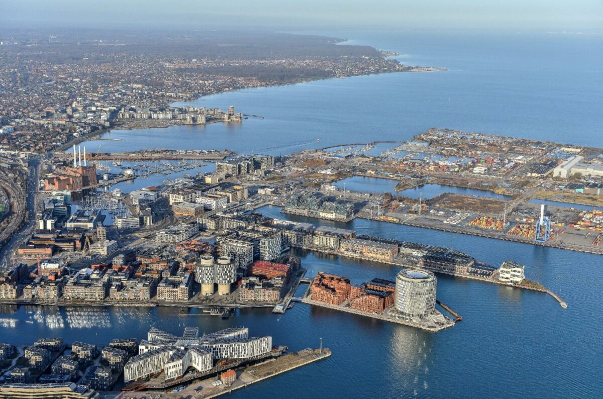 Luftfoto af Nordø i København med boligerblokke, det runde kontorfællesskab Spidsen - omgivet af vand på alle sider.