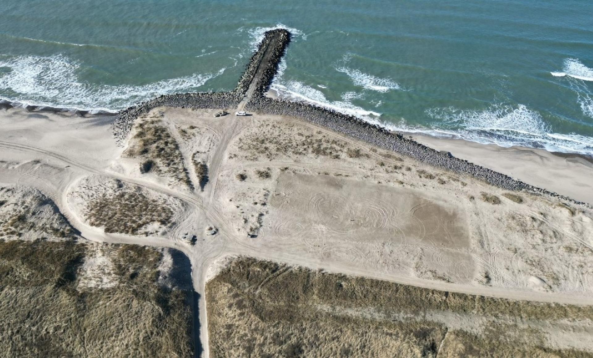 Det 24.300 kvm kemikaliedepot ved Høfde 42 er i dag dækket med sand. En jernvæg, der blev banket 14 meter ned i jorden i 2006, skal sikre, at giften ikke siver ud i havet. Foto: Frederik Grønfeldt Ahrenkiel, Region Midtjylland.