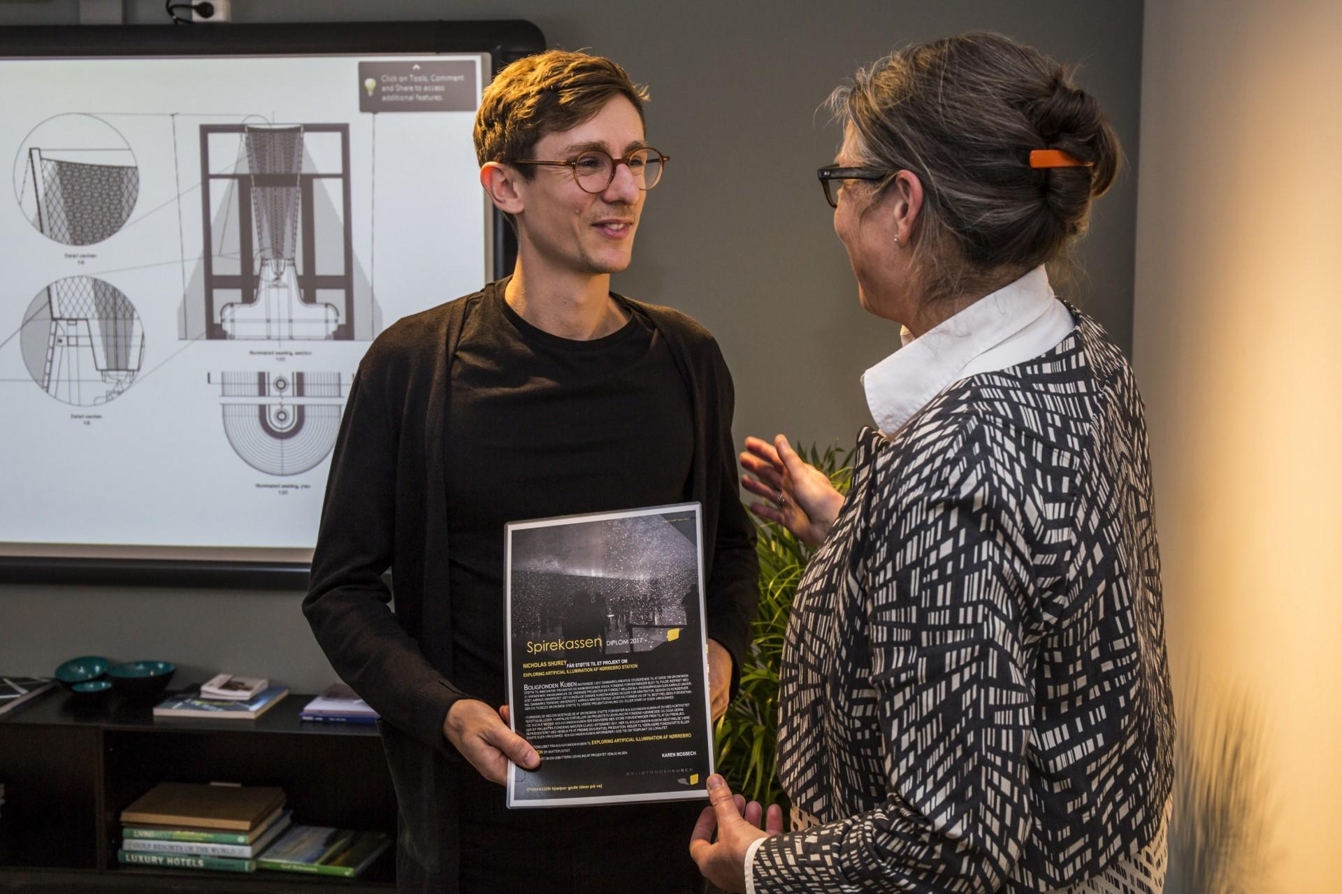 Nicholas Shurey får overrakt Spirekassen for sit lysprojekt på Nørrebro Station af formanden for Boligfonden Kuben Karen Mosbech. Foto: Kontraframe.