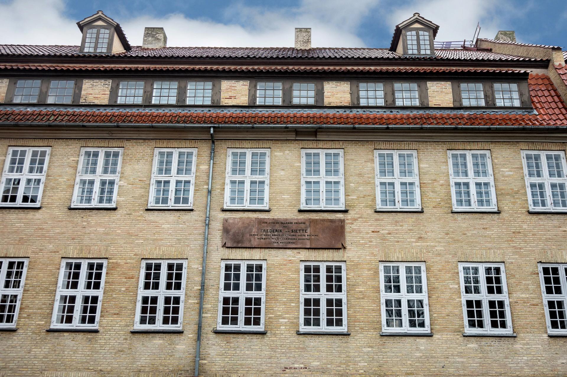 Garnisonshaven indrettes i to fredede bygninger fra henholdsvis 1760 og 1660, og inskriptionen på facaden mod Rigensgade vidner om Frederik VI's etablering af 'Garnisonshospitalet' i 1817.