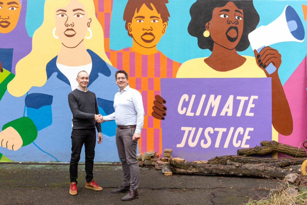 Anton Ryslinge og Peter Vangsbo giver hånd, foran et vægmaleri hvorpå der står "Climate Justice".