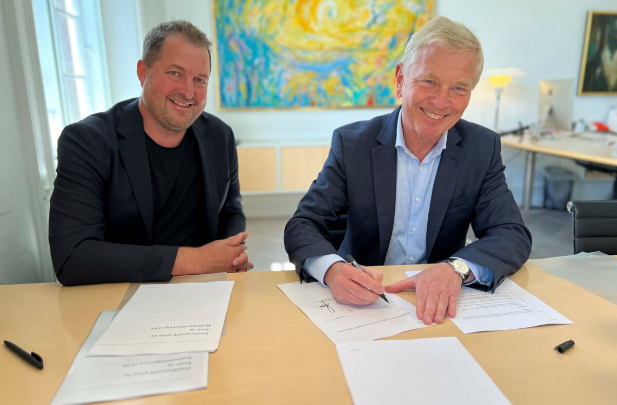 To mænd - Jakob Andersen fra Aart og fsb’s administrerende direktør Bjarne Larsson underskriver aftale om totalrådgivning. I baggrunden et gult og blåt maleri. På det træfarvede bord ligger papirer til underskrift