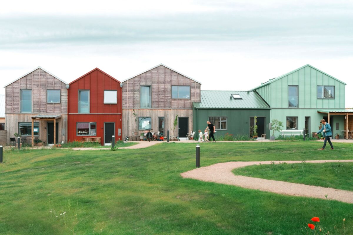 Fire farvestrålende huse på række, med græsareal foran.