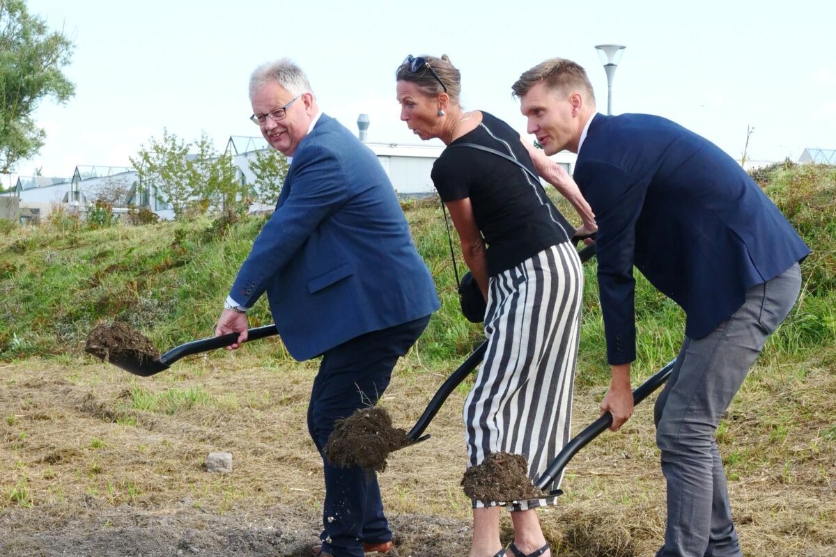 To mænd og en kvinde bærer hver en spade med jord på.