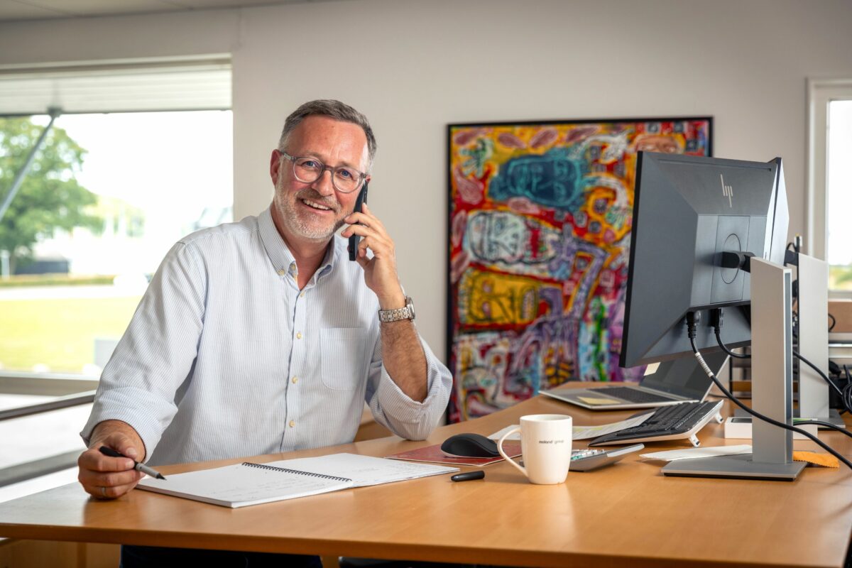 Brian Nissen smiler og holder en telefon op til øret.