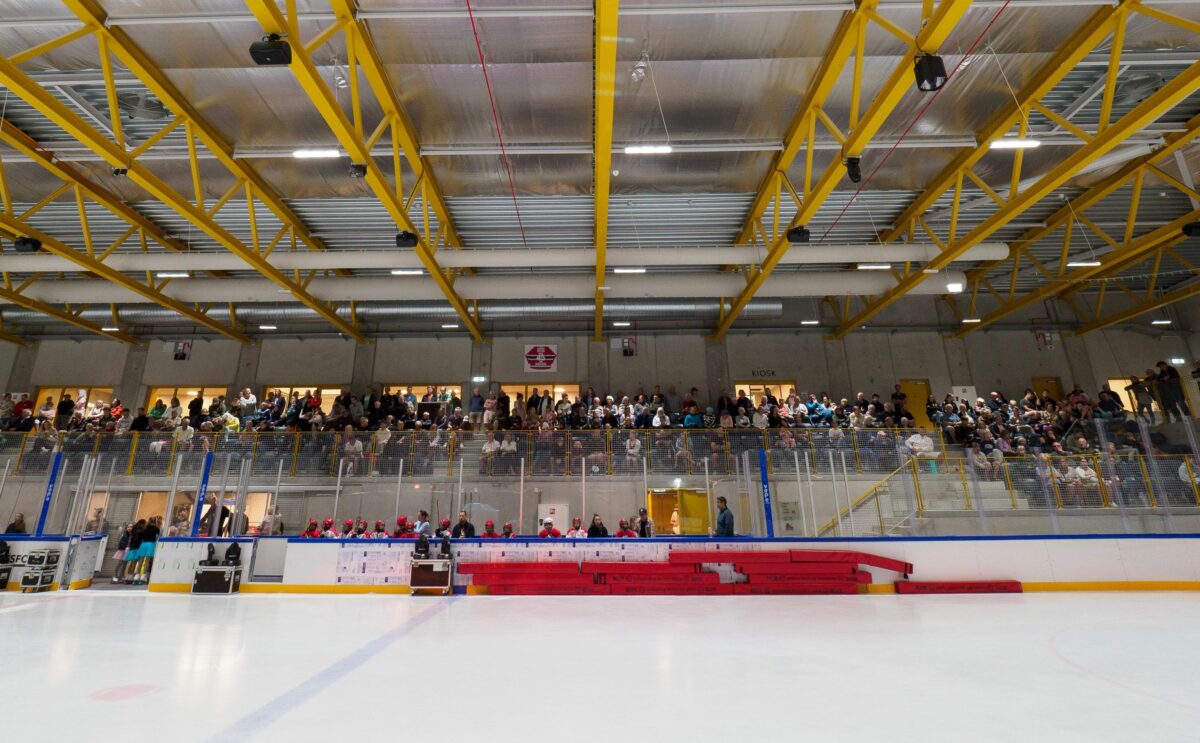 Foto fra skøjtebanen. Hallen har gule spær og tilskuere til indvielsen på tilskuerpladserne