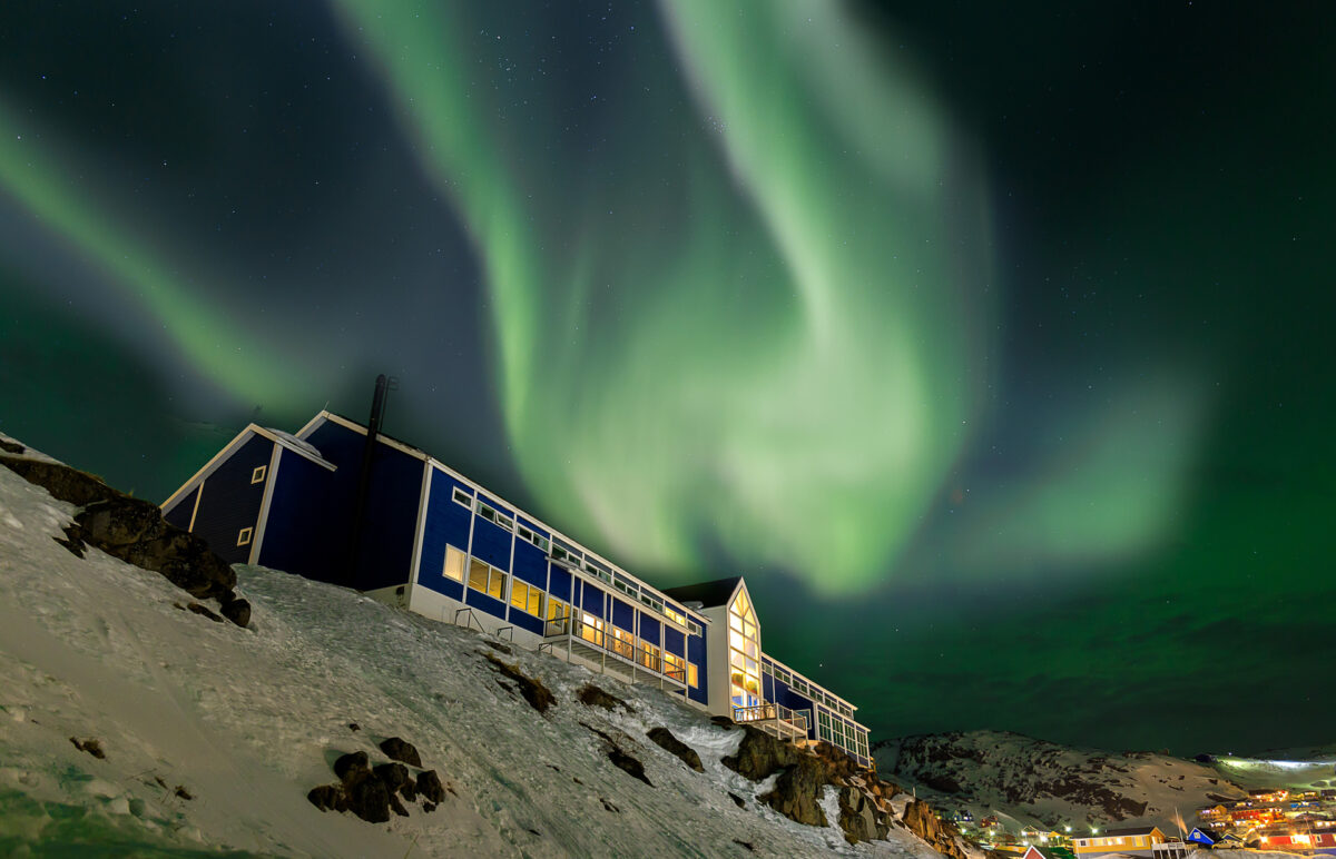 Hotel Qaqotoq med nordlys på himlen bag sig