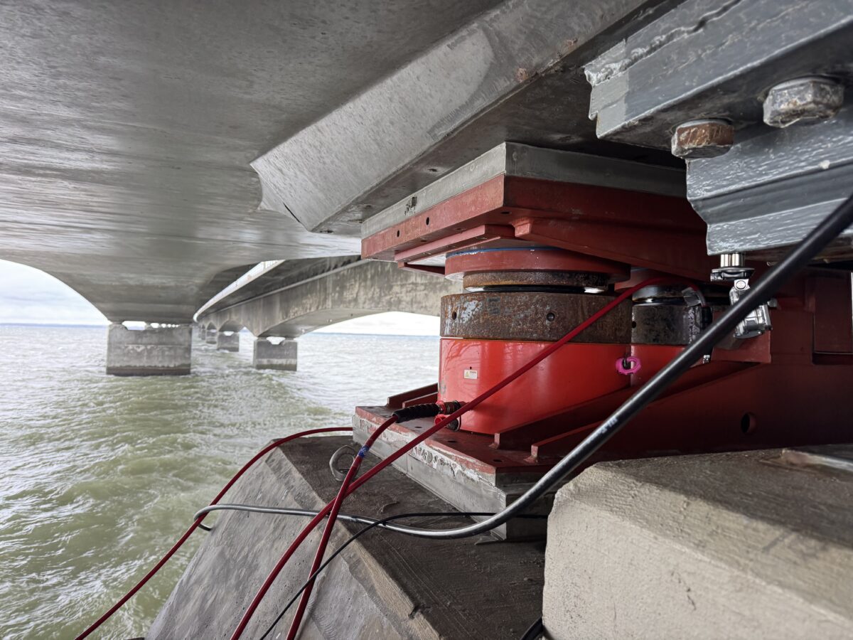 Foto nede under broen, hvor en rød donkraft er sat op på en betonpille. Man ser undersiden af broen og vandet under