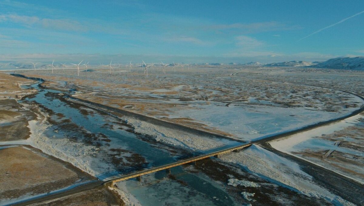 Foto ud over det øde islandske landskab med sne, is og en samling vindmøller i horisonten