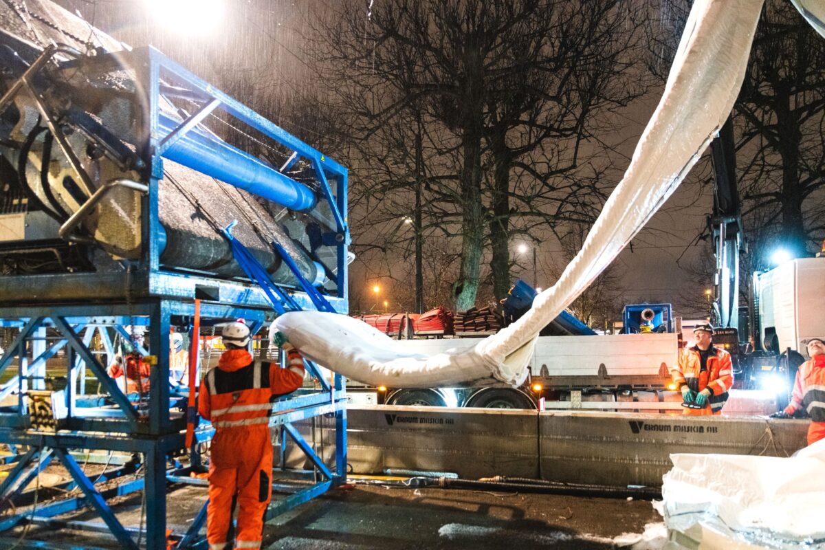 En flok mænd i orange arbejdstøj på en byggeplads.