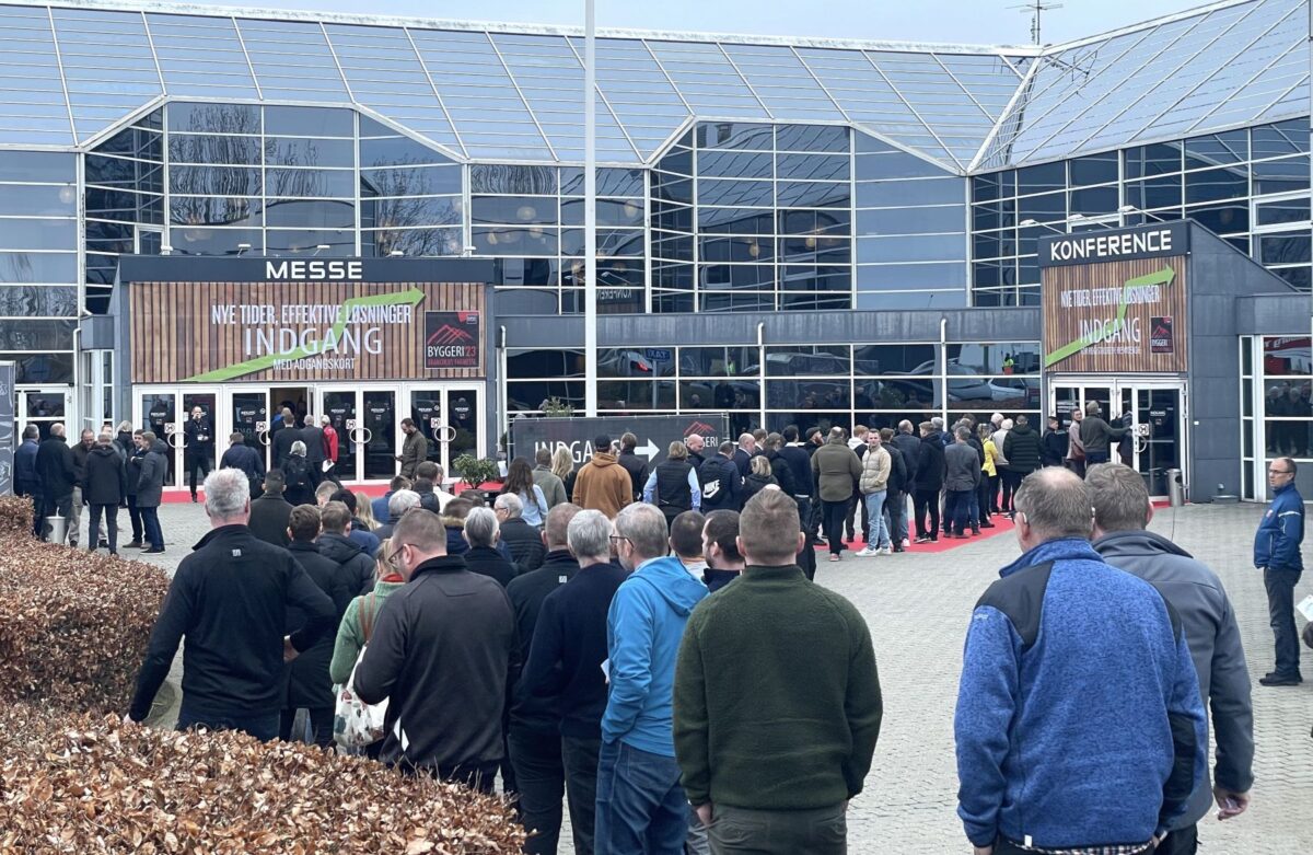 En lan kø af mennesker venter under åben himmel for at komme ind på Byggeri-messen