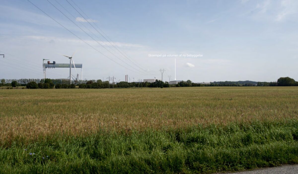 Foto af grønt område. I horisonten ses en stor kran og der er tegnet en 50 meter høj bygning ind, så man kan se, hvordan det vil se ud. Bygningen er markeret med en pil