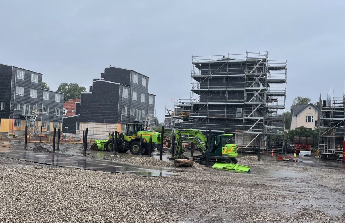 Foto af grå, lave boligblokke under opførelse. Nogle af blokkene er omgivet af stilladser, andre er ikke