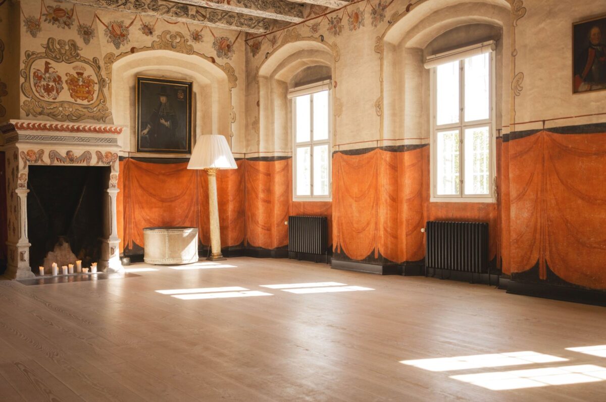 Foto af gammel sal med orange vægge på den nederste halvdel - loft og den øverste del er lys. Der er masser af udsmykning op mod og i loftet