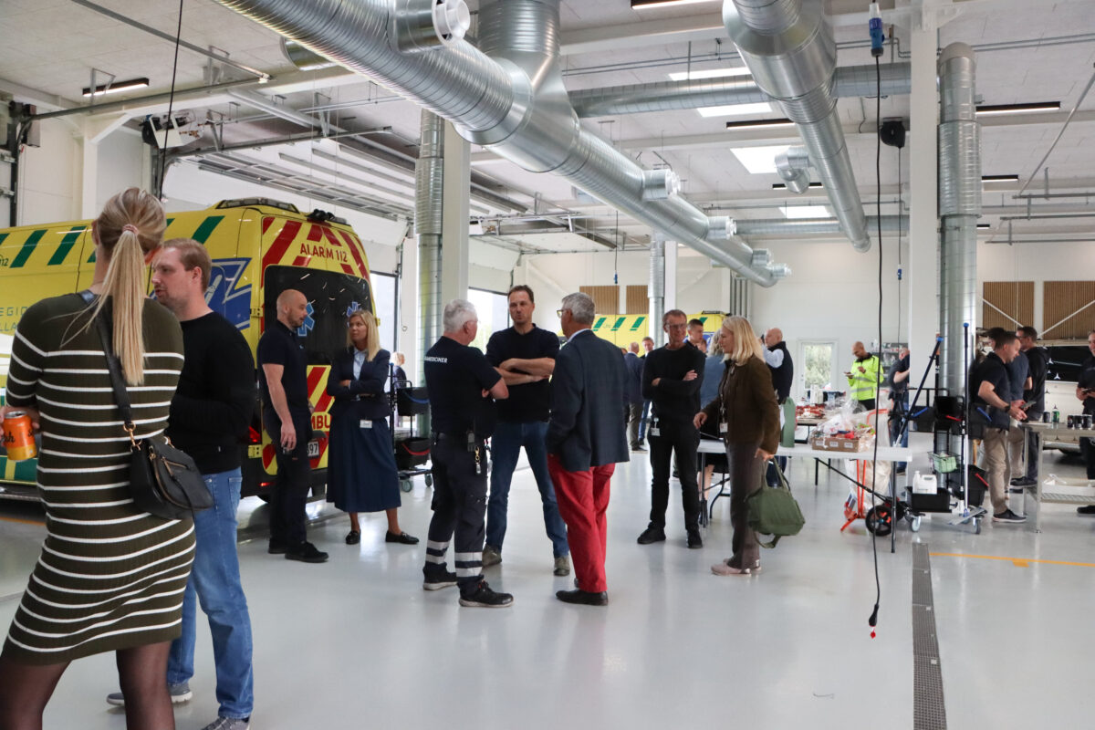 En gruppe mennesker står i den nye ambulancebase.