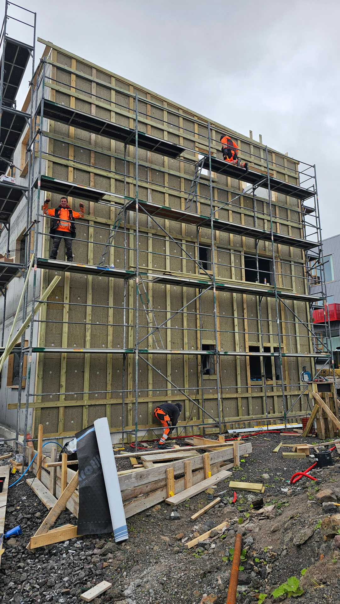 Personer arbejder på stillads foran bygning