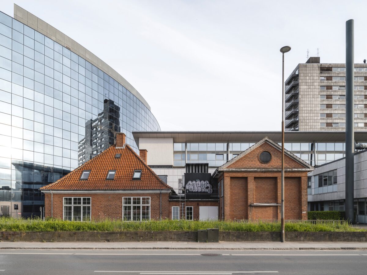 En rød murstensbygning foran en stor bygning med glasfacader