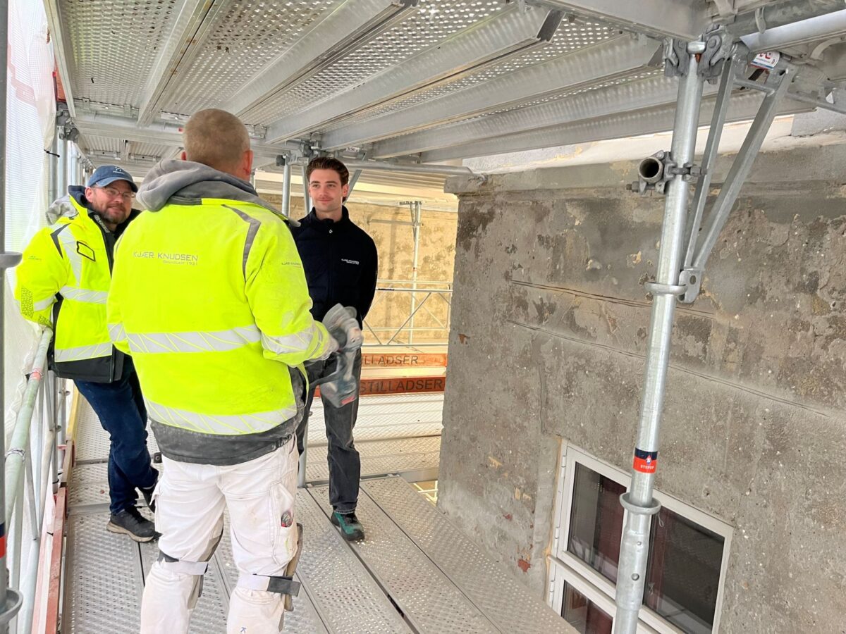 Tre personer i samtale omkring byggeprojekt