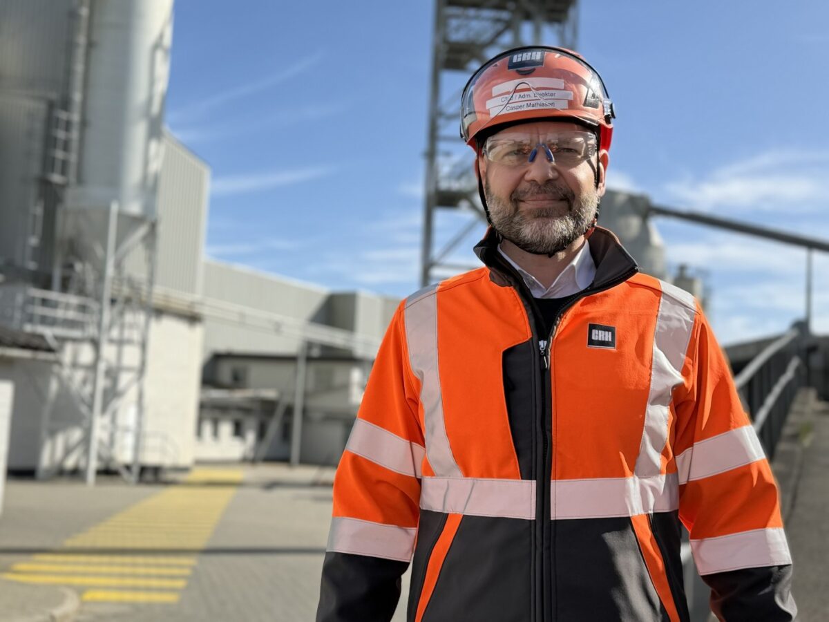 Person i arbejdstøj foran bygninger